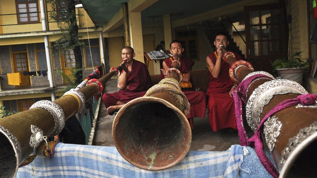 Monges budistas tocam instrumento tradicional usado para orações perto do templo de Tsuglagkhang McLeodganj, na Índia