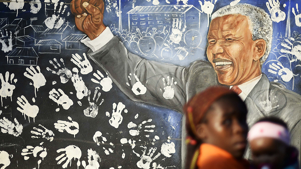 Moradores passam por um mural fora da casa do ex-presidente Nelson Mandela, no município de Joanesburgo, África do Sul