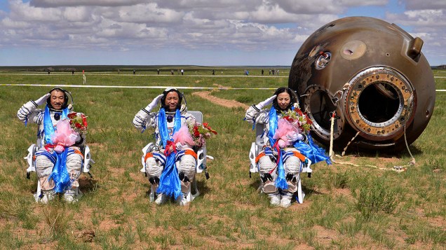 Astronautas Zhang Xiaoguang, Nie Haisheng e Wang Yaping saudam depois de voltar à Terra na cápsula da nave espacial Shenzhou-10 na  região autônoma da Mongólia, norte da China, após missão de 15 dias em que atracou com um laboratório espacial tripulado