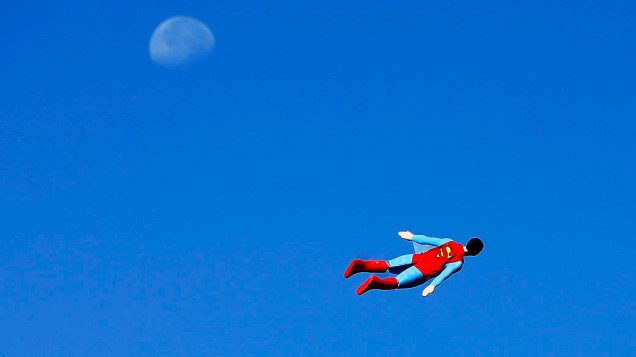 Avião controlado por rádio no formato de Superman pilotado pelo designer Otto Dieffenbach, passa pela lua durante um vôo de teste em San Diego, Califórnia