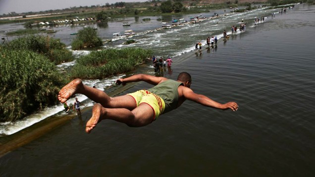Menino salta no rio Nilo, onde pessoas celebram o feriado de primavera de Sham el-Nessim nos arredores de Cairo, no Egito