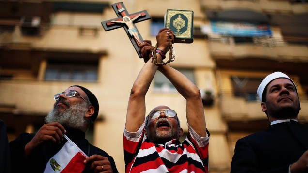 Manifestante segura uma cruz e o Alcorão durante um protesto exigindo que o presidente Mohamed Mursi renuncie, na praça Tahrir, no Cairo