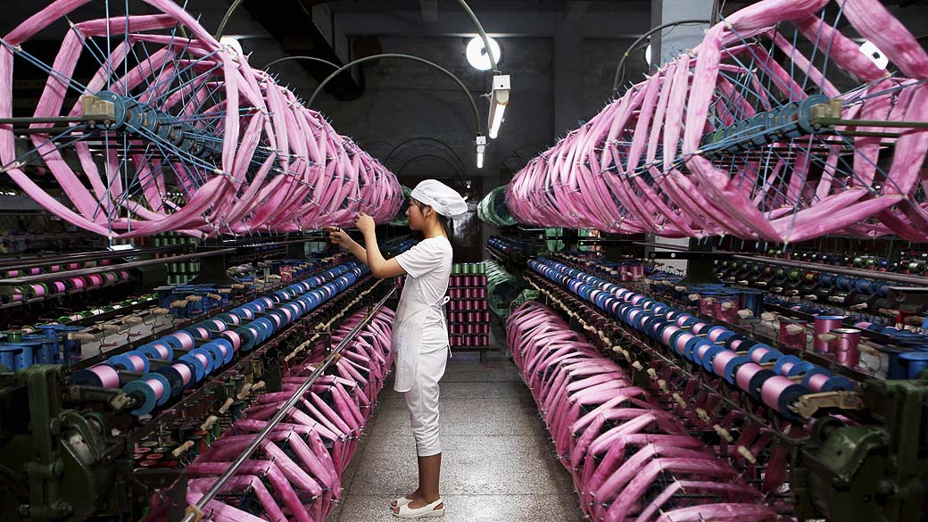 Mulher alinha tecido dentro de uma fábrica de seda em Neijiang, província de Sichuan