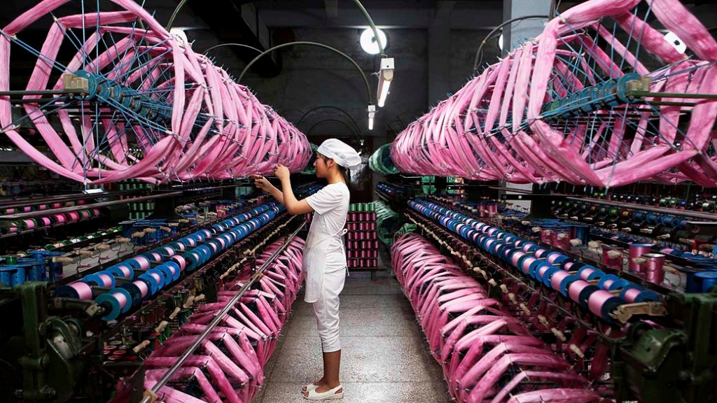 Exportações em alta: mulher alinha tecido em uma fábrica de seda em Neijiang, província de Sichuan, na China