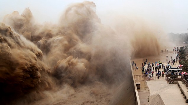Visitantes assistem a água jorrando no Reservatório Xiaolangdi sobre o Rio Amarelo, durante uma operação de lavagem de areia em Jiyuan, província de Henan, na China