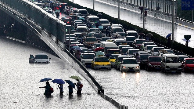 Pessoas andando por uma via inundada, em Wuhan, província de Hubei, centro da China, após uma forte tempestade, no domingo (07)