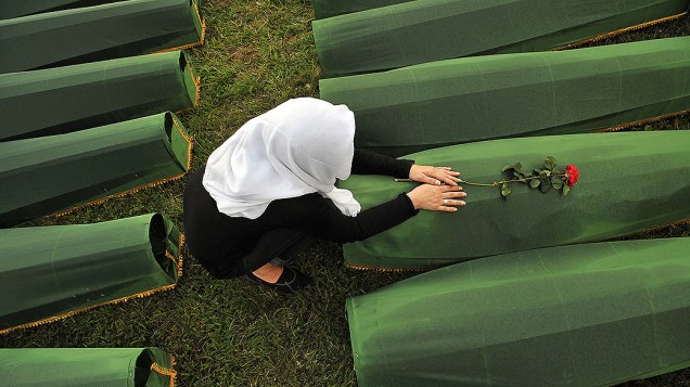 Muçulmana sobrevivente do massacre de Srebrenica em 1995, chora sobre o caixão de um parente, no cemitério memorial na vila de Potocarion perto da cidade oriental-bósnia de Srebrenica, na quarta-feira (10)