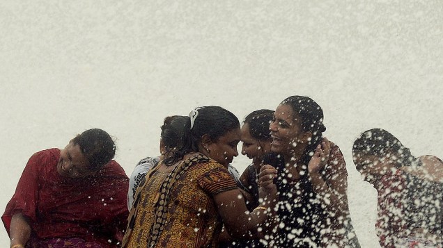 Mulheres são atingidas por onda nesta sexta-feira (12), durante as chuvas de monções em Mumbai, na Índia