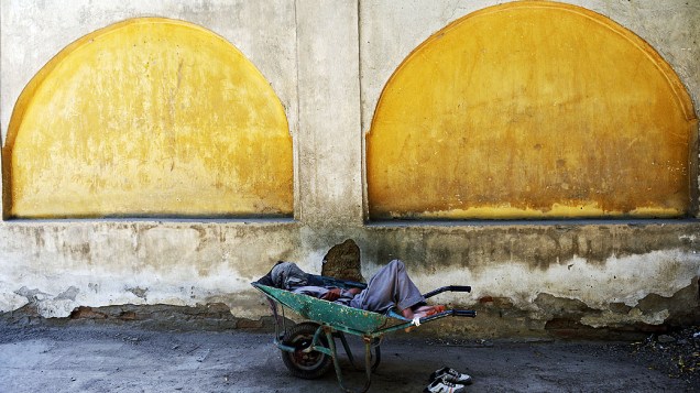 Um trabalhador afegão dorme em seu carro em uma mesquita em Cabul nesta segunda-feira (15)