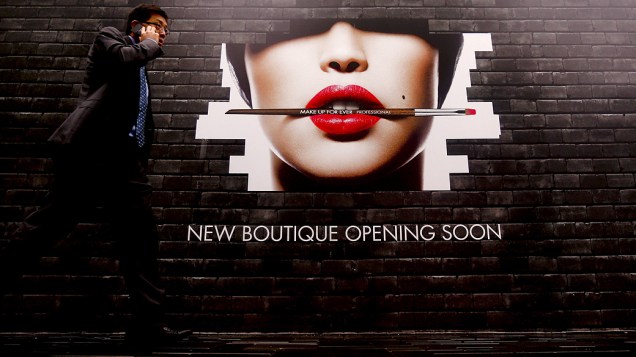 Homem passa em frente a anúncio da abertura de uma nova loja em Pequim, na China