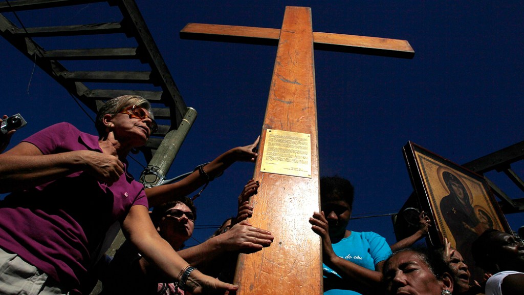 Fieis carregam os símbolos da Jornada Mundial da Juventude, a cruz peregrina e o ícone de Nossa Senhora durante visita á favela do Vidigal no Rio de Janeiro, nesta segunda-feira (15)