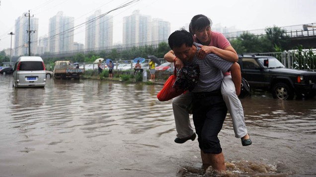 Homem carrega uma mulher em uma área alagada nesta terça-feira (16), em Pequim. Pelo menos 295 pessoas foram mortas ou desaparecidas após chuvas e o Tufão Soulik atingir a China
