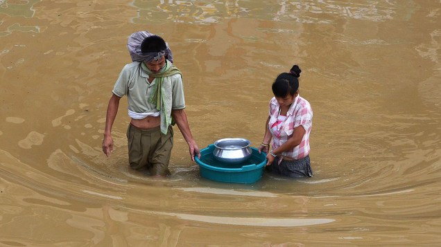 Residentes transportam água potável em um balde pela enchente, depois da chuva de monção atingir Dimapur nesta quarta-feira (17), em Nagaland. Centenas de pessoas ficaram desabrigadas durante as fortes chuvas de monções, que continuam atingindo a Índia