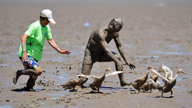 Participantes tentam apanhar patos em um campo enlameado, durante Carnaval na lama nesta quarta-feira (17),  em um parque em Daishan, na China