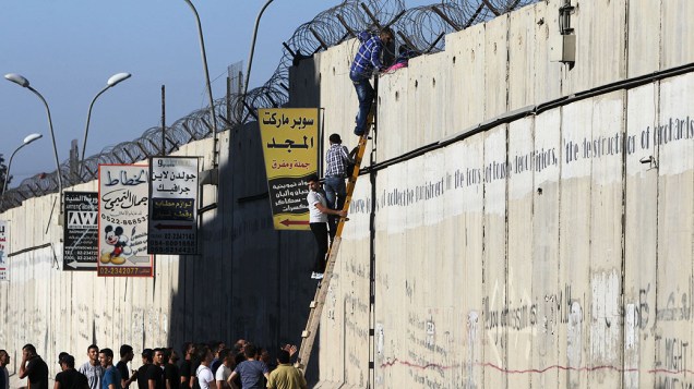 Palestinos tentam escalar muro de separação de Israel para alcançar a mesquita de al-Aqsa, na Cidade Velha de Jerusalém, nesta sexta-feira (26), na terceira sexta-feira do mês sagrado do Ramadã