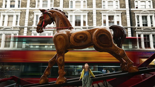 Criança senta em uma cadeira balanço gigante em forma de cavalo fora de Christie Auction House, em Londres, Inglaterra. O cavalo faz parte do Out of the Ordinary e sua venda deverá render entre 25 e 40 mil libras
