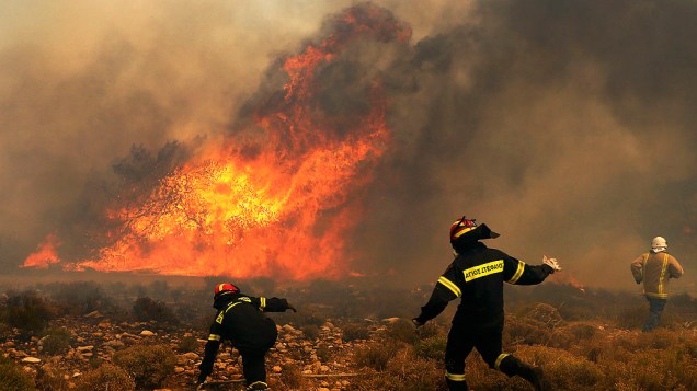 Bombeiros tentam conter incêndio florestal em Marathon, perto de Atenas. Os fortes ventos alastraram o fogo, danificando casas