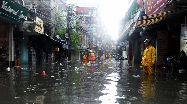 Trabalhadores do serviço ambiental municipal prestam socorro em uma rua inundada após um tufão atingir o centro de Hanói, trazendo fortes chuvas ao Vietnã