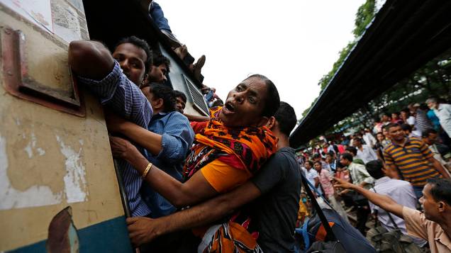 Passageiros seguram-se na porta de um trem superlotado em Dhaka. Milhões de moradores viajam à capital para celebrar o Eid al-Fitr, fim do mês de jejum do Ramadã, em Bangladesh
