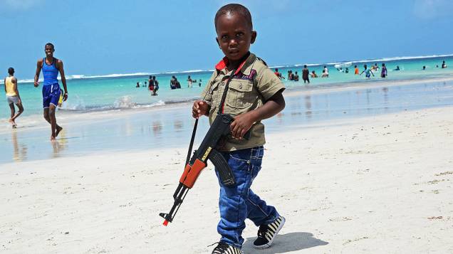 Menino anda com uma arma de brinquedo ao longo da Praia Lido, perto de Mogadíscio, na Somália