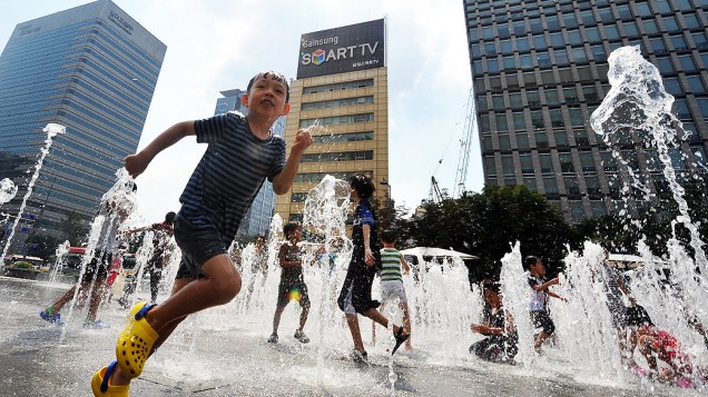 Crianças se refrescam em fonte nesta segunda-feira (12) em Seul (Coreia do Sul). A onda de calor que atinge o país fez a temperatura atingir 40ºC em algumas regiões