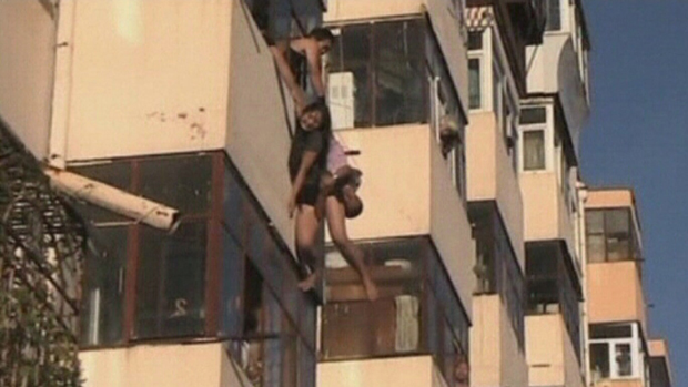 Imagem divulgada nesta segunda-feira (12), chinesa escorrega da sacada e namorado tenta resgatá-la. O casal foi retirado por vizinhos, em Harbin