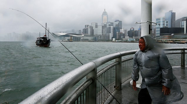 Homem tenta pescar durante fortes ventos em Hong Kong, nesta terça-feira (13). A cidade se prepara para a chegada do tufão Utor