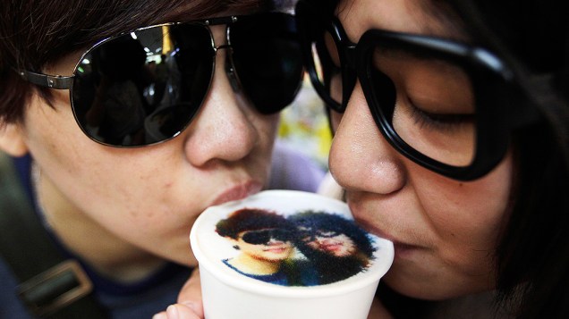 Um casal bebe uma xícara de café com leite com a sua foto impressa na parte superior da espuma de leite em um estabelecimento de Taipei (Taiwan)