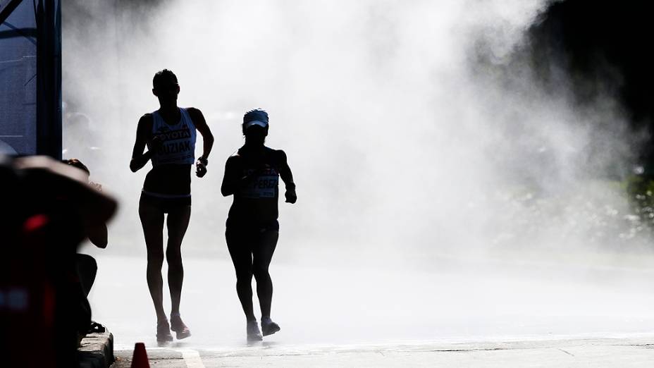 Competidores se refrescam em chuveiro instalado no meio da pista durante o Campeonato Mundial de Atletismo em Moscou, na Rússia, nesta terça-feira (13)