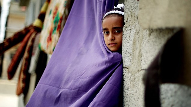 Menina palestina olha para fora de sua casa no campo de refugiados de Shati na Cidade de Gaza, nesta quinta-feira (29)