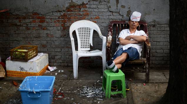 Cozinheiro descansa fora de um restaurante em Pequim. A China teve uma redução do crescimento econômico em comparação com o ano passado