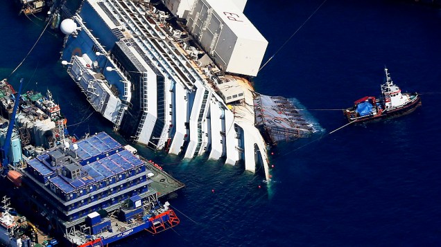 Imagem aérea divulgada nesta quinta-feira (12), mostra o navio Costa Concordia, que permanece há um ano e meio tombado à beira da ilha de Giglio, na Itália