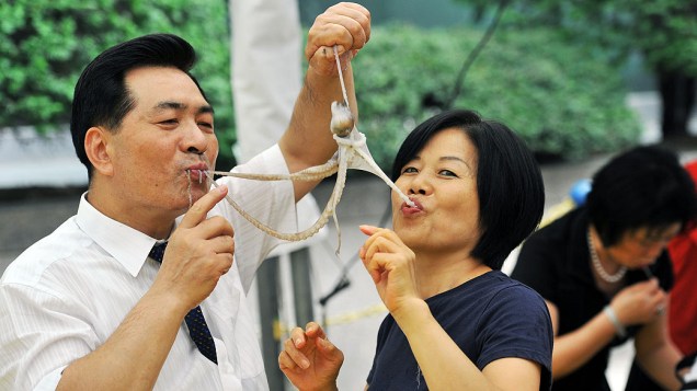 Casal sul-coreano come um polvo vivo durante um evento para promover um festival de comida local em Seul, na Coreia do Sul, nesta quinta-feira (12)