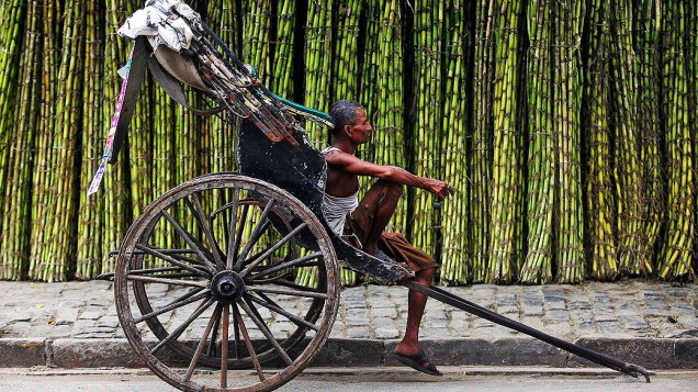 Puxador de riquixá espera por clientes em um mercado de cana em uma estrada de Calcutá, na Índia, nesta segunda-feira (16)