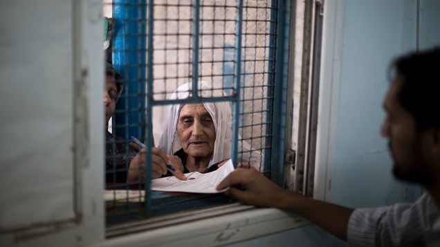Mulher palestina espera para receber ajuda alimentar em um centro de distribuição de ajuda da ONU na Cidade de Gaza