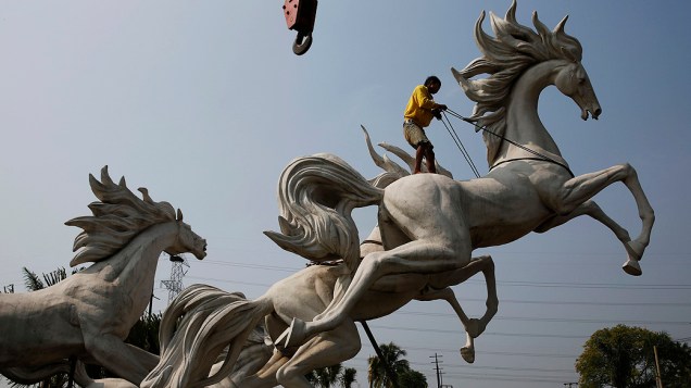 Homem trabalha na montagem de uma estátua de cavalos em um novo complexo habitacional em Parung, província de Java, na Indonésia