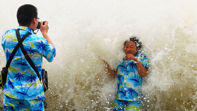 Turistas tiram fotos onde uma tempestade atinge a costa, sob a influência de Tufão Wutip em Sanya, província de Hainan, na China