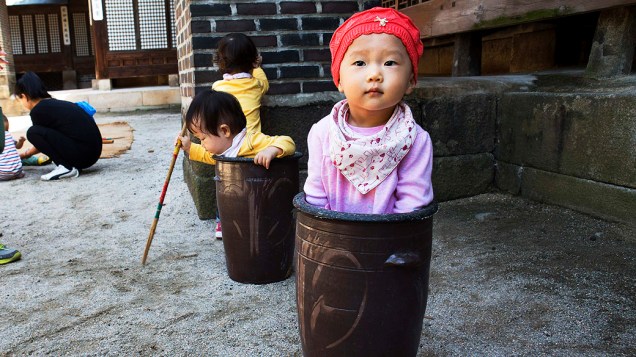 Jung Ha-Yoon, de 2 anos, é vista dentro de um recipiente de cerâmica enquanto brincava com outras crianças nos esportes tradicionais do Royal and Food Festival realizada no Unhyeon Palace, em Seul