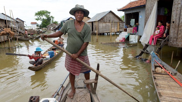 Homem atravessa de barco uma inundação em uma aldeia de Kandal. Mais de 80 pessoas morreram em recentes inundações causadas pelas fortes chuvas transbordando o Rio Mekong, no Camboja