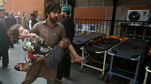 Homem carrega uma menina, que foi ferida na explosão de uma bomba, em Peshawar. A bomba explodiu perto de uma equipe de vacinação contra a poliomielite ao noroeste da cidade de Peshawar, matando duas pessoas. A polícia diz ser o mais recente de uma série de ataques contra os trabalhadores de saúde, no Paquistão