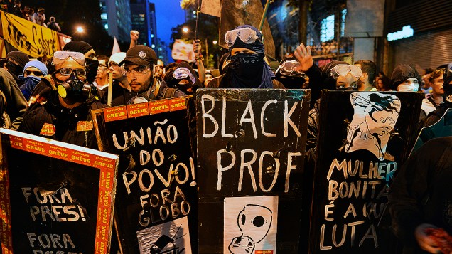 Manifestantes seguram cartazes durante um protesto de professores, exigindo melhores condições de trabalho e contra a violência da polícia no Rio de Janeiro