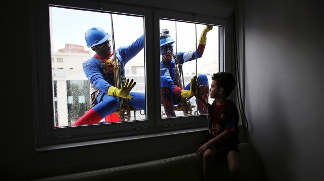 Homens fantasiados como Super Homem e Capitão América interagiram com as crianças enquanto faziam o trabalho de limpar a fachada do Hospital Infantil Sabará, em São Paulo na véspera do Dia das Crianças
