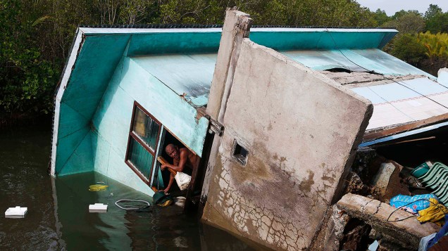 Homem olha da janela de sua casa, que desabou em um rio, em Buenavista, Bohol um dia depois do terremoto atingiu a região central Filipinas Homem olha da janela de sua casa, que desabou em um rio, em Buenavista, Bohol um dia depois do terremoto atingiu a região central Filipinas
