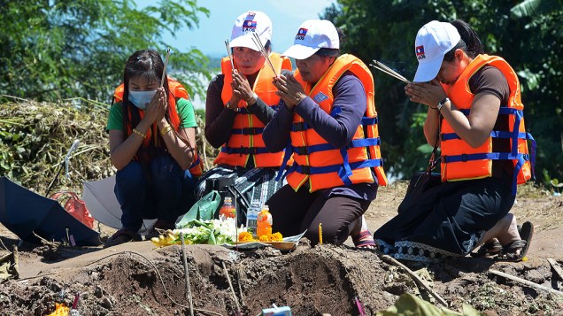 Parentes dos passageiros do acidente de avião da Lao Airlines fazem orações perto do local da tragédia que deixou 17 mortos, no Pakse, em Laos