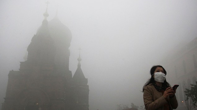 Mulher usa máscara durante dia de forte poluição, no centro de Harbin, na China