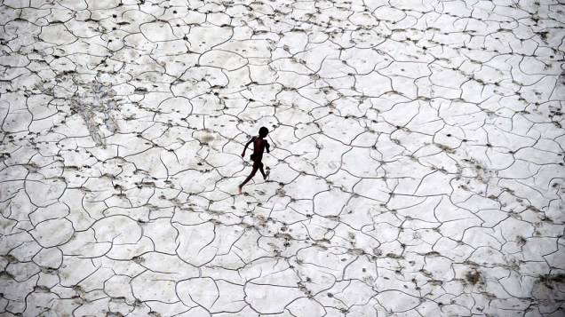 Uma criança correndo em um leito de rio seco em Allahabad na Índia