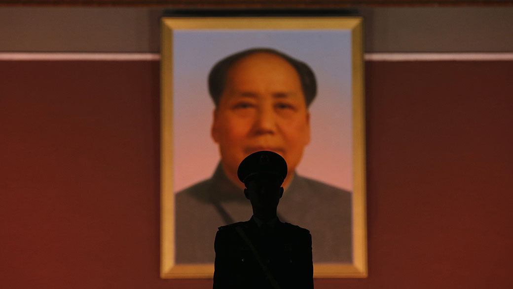 Policial paramilitar fica de guarda em frente ao retrato gigante de Mao Tsé-Tung, na entrada principal da Cidade Proibida, em Pequim, China
