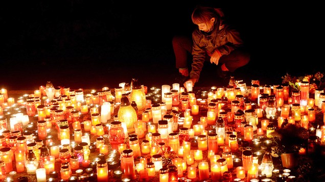 Jovem acende velas, na véspera do Dia de Finados, celebrado pelos católicos como Dia de Todos os Santos, no Cemitério Olsany em Praga, República Checa 