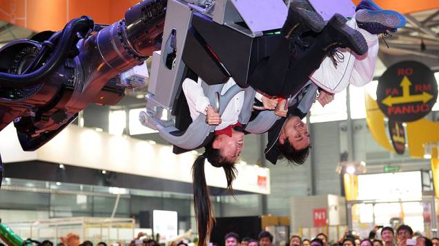 Visitantes montam em um braço do robô chamado Robocoaster na Feira Internacional da Indústria da China, em Xangai, nesta quarta-feira (06)
