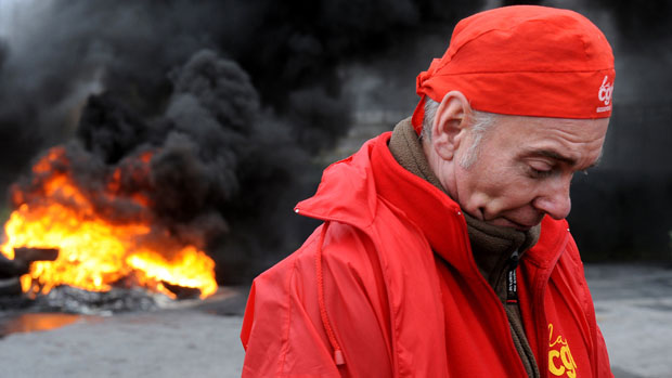 Em Amiens, homem passa por uma pilha de pneus queimados em protesto contra o fechamento da fábrica da Goodyear, na França